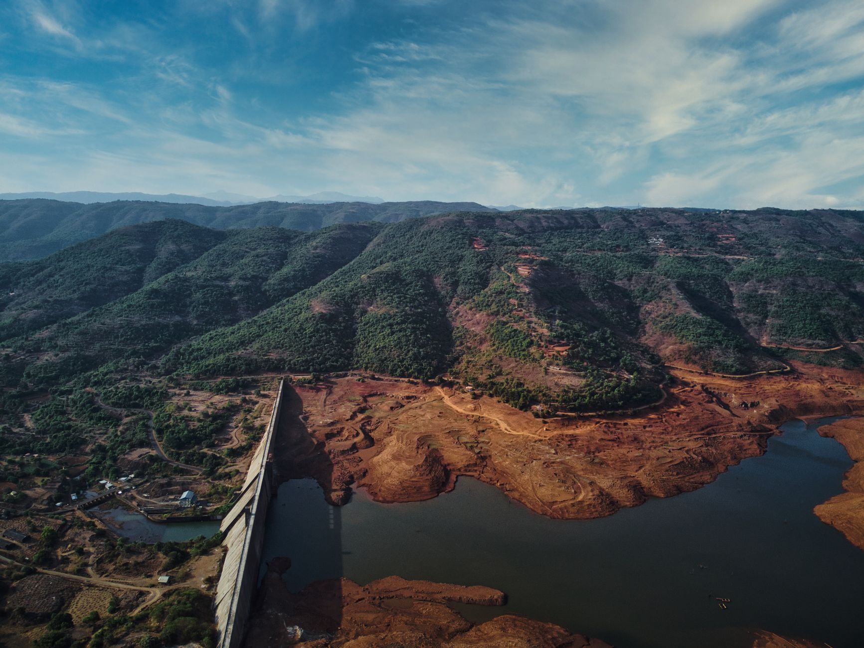 A dam and reservoir surrounded by green hills